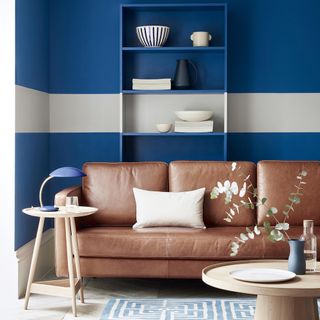 living room with blue wall and white stripe brown sofa with white cushion and shelve