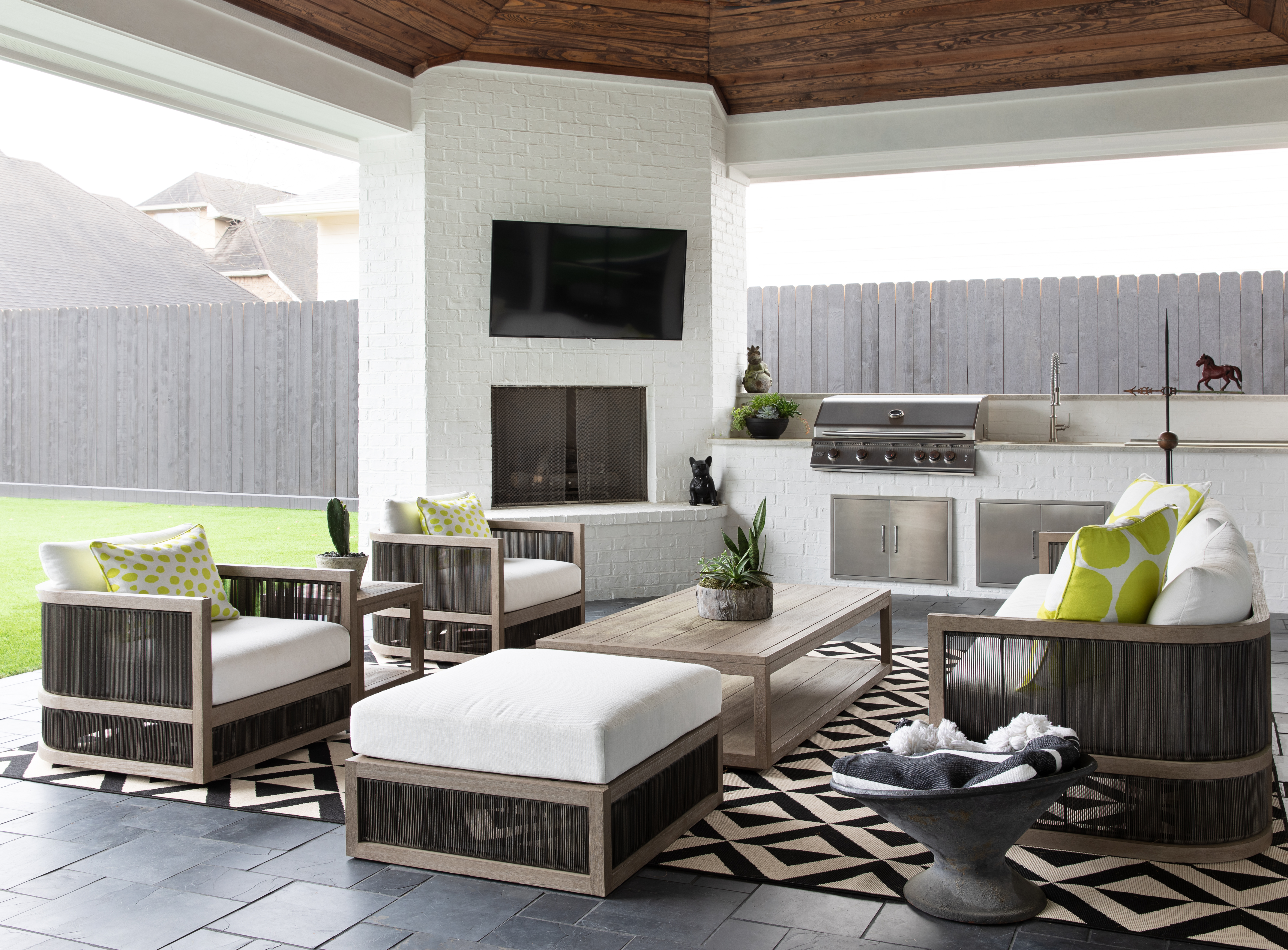An outdoor space with a built in grill, storage, BBQ and a large seating area