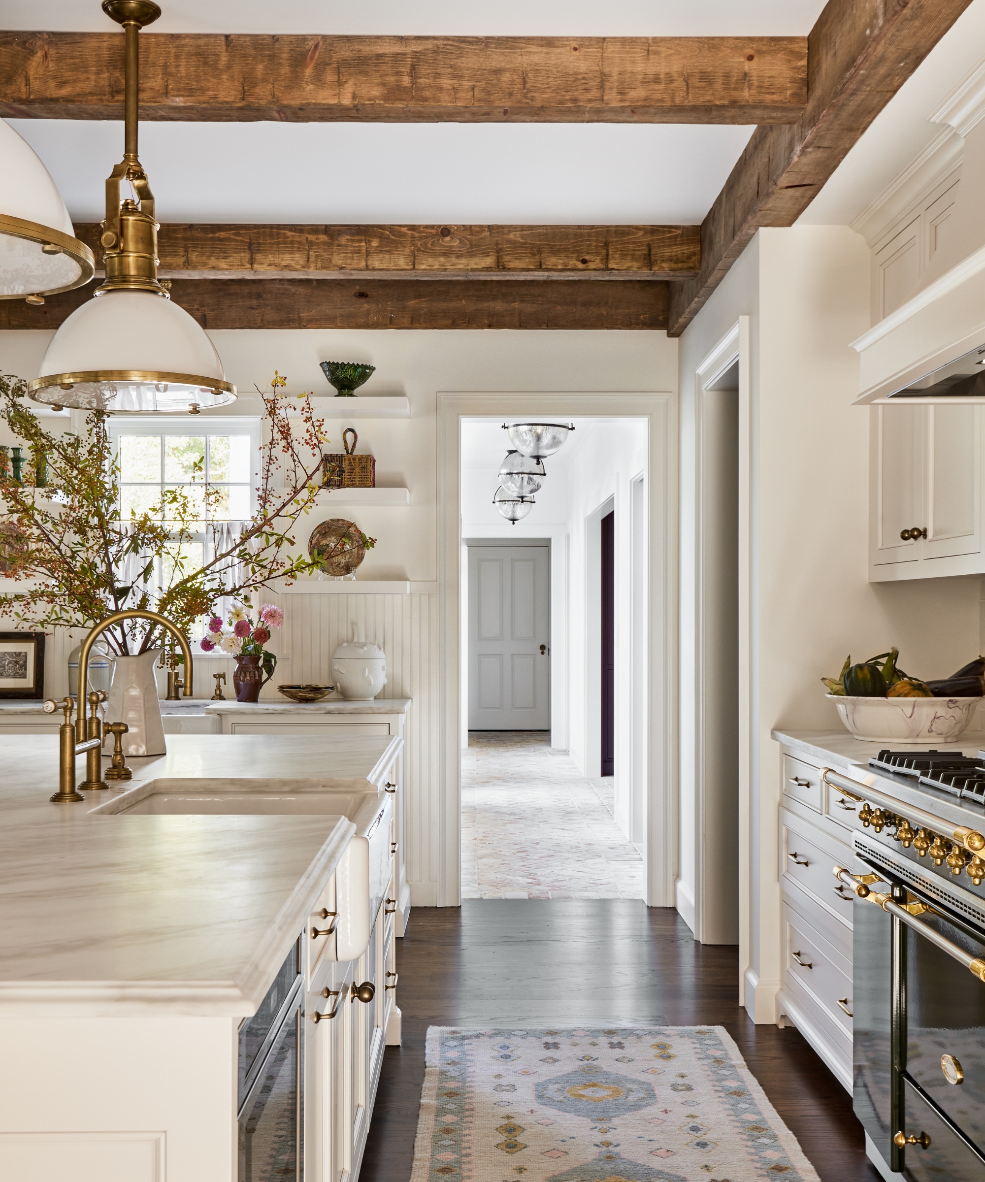 A white kitchen with wooden ceiling beams and carefully edited decor for fall hosting
