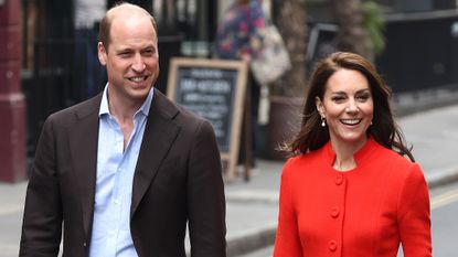 Prince William, wearing a suit, and Catherine, Princess of Wales, wearing a red coat, arrive at the Dog &amp; Duck pub during their visit to Soho on May 04, 2023