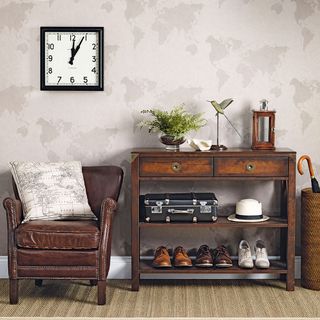 antique themed hallway with a brown arm chair and brown table with a world map printed wallpaper