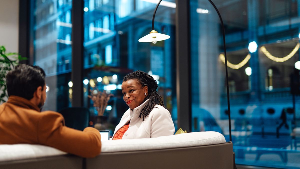 HR professional conducts meeting with a job applicant in an open plan office space.