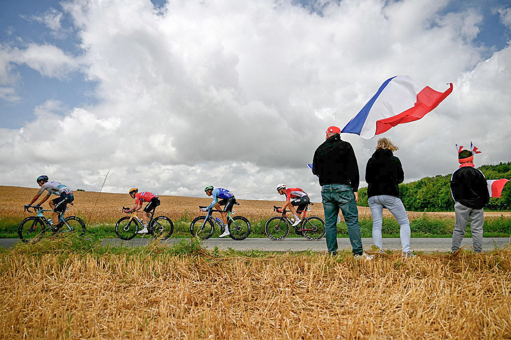 TOPSHOT - Spectators hold a French flag as they watch XDS Astana Team&#039;s Kazakh rider Yevgeniy Fedorov (L), Uno-X Mobility team&#039;s Norwegian rider Andreas Leknessund (2nd L), Decathlon AG2R La Mondial Team&#039;s French rider Bruno Armirail (2nd R) and Lotto team&#039;s Belgian rider Brent Van Moer (R) cycle by in a breakaway during the 2nd stage of the 112th edition of the Tour de France cycling race, 209.1 km between Lauwin-Planque and Boulogne-sur-Mer, Northern France, on July 6, 2025. (Photo by Loic VENANCE / AFP) (Photo by LOIC VENANCE/AFP via Getty Images)