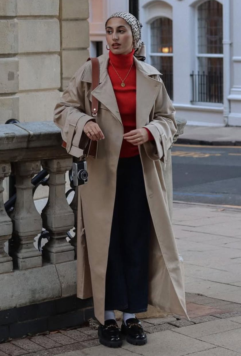 @modestmira_ wears a beige trench coat, red turtleneck jumper, black midi skirt, grey chunky socks and black chunky loafers