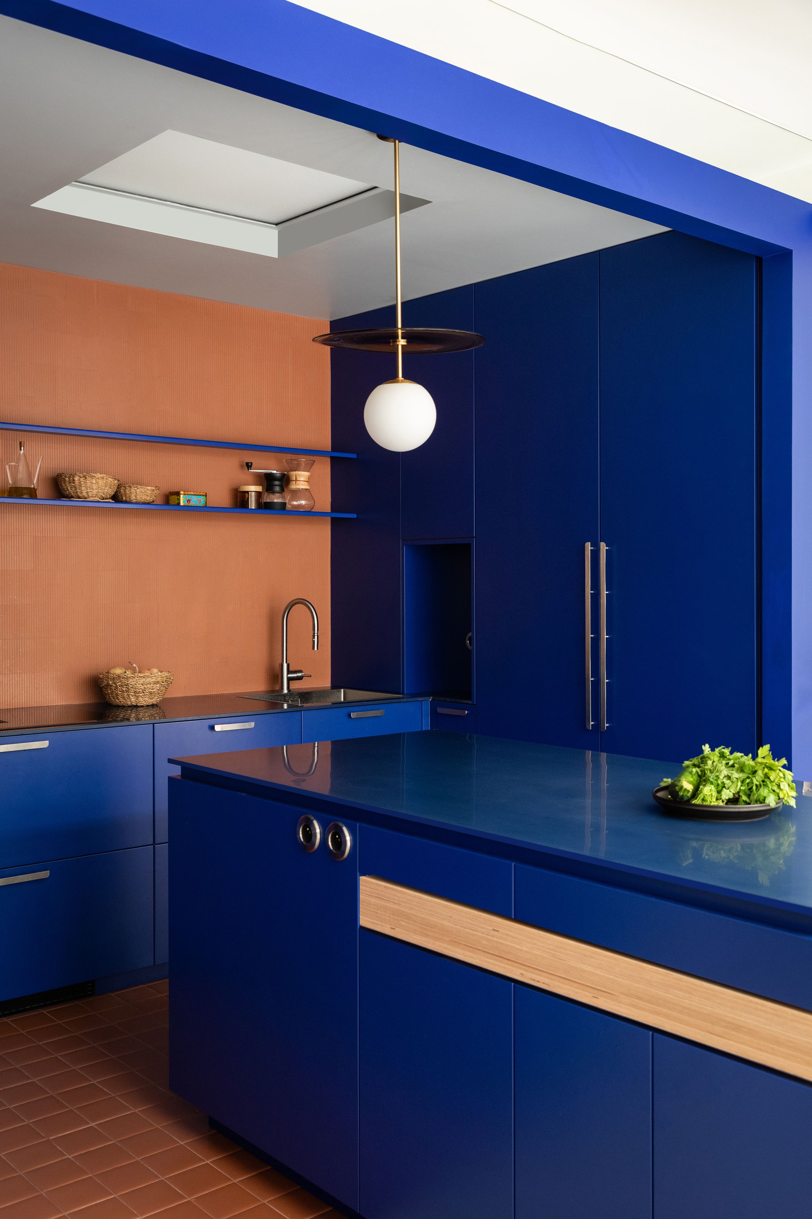 Two kitchens with orange walls, and electric blue cabints, island and shelves
