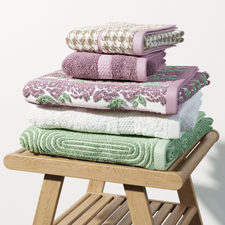 five bath towels stacked on a wooden stool