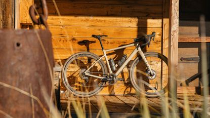 Enve MOG gravel bike leaning against a wooden building in dappled sunlight