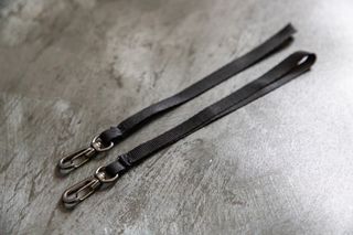 A close up of the two safety tether straps that come with the BlackRapid Blackline II Double Camera Harness on a metal background