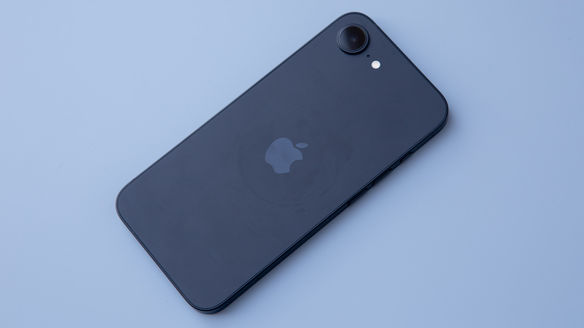 iPhone 16e in black on blue background