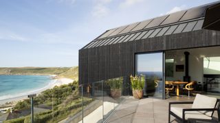 modern self build on coastal cliff with black roof, black cladding ans solar panels,
