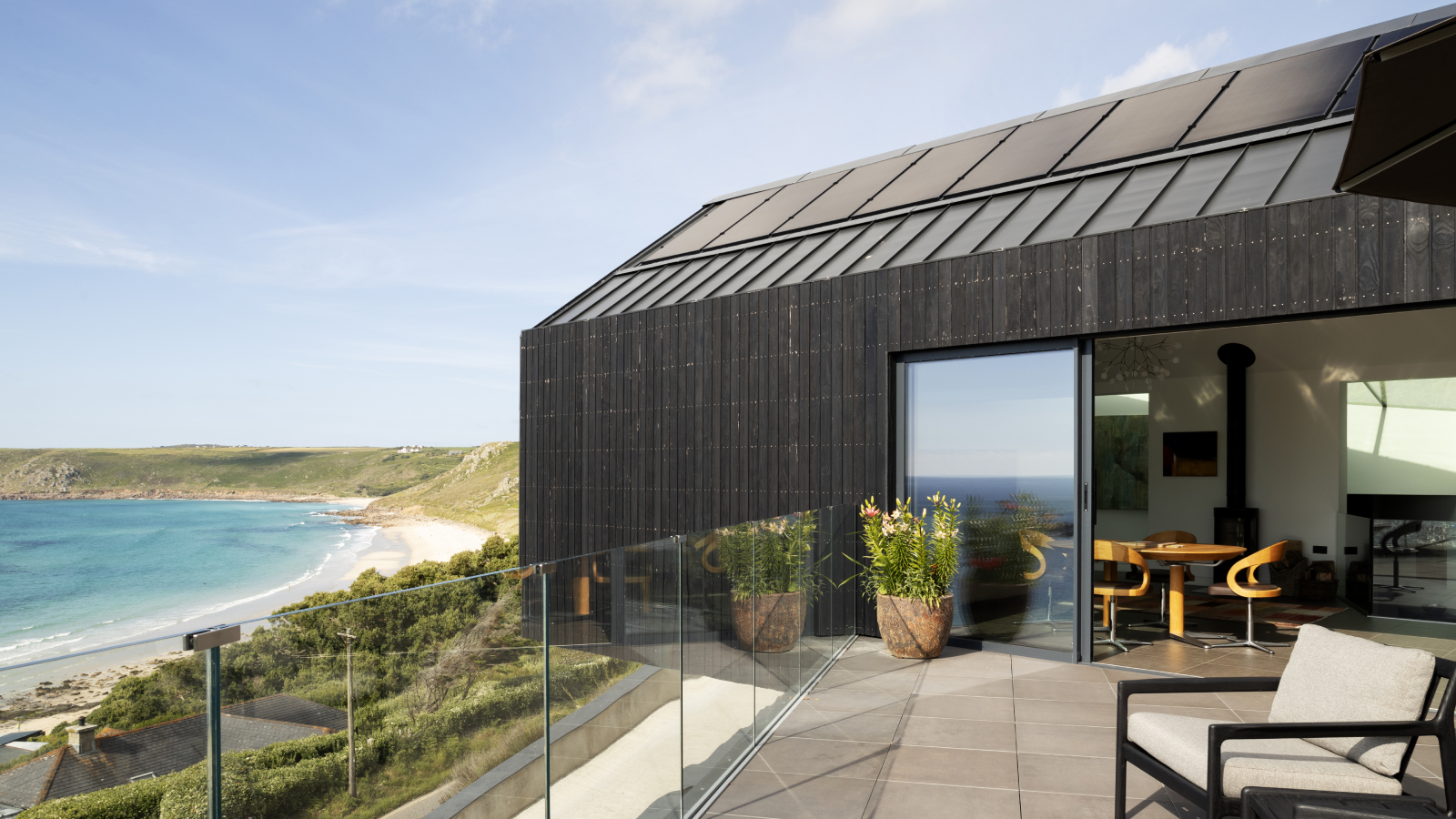 modern self build on coastal cliff with black roof, black cladding ans solar panels,