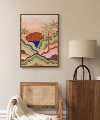 A colorful artwork above a wooden chair and side table with a lamp