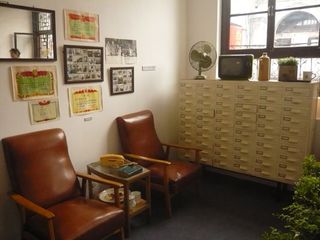 Two leather chairs, a table with a vintage phone, and a large filing cabinet