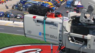 A shotgun microphone flat on a camera lens. 