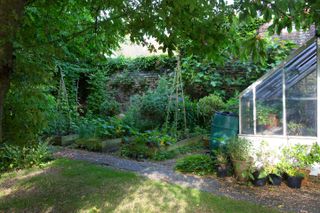 cottage garden with raised beds and lean to greenhouse