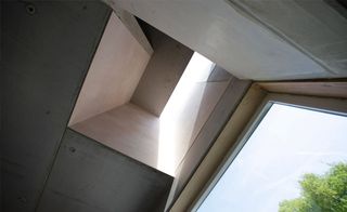Inside, the concrete work has been left largely unadorned, paired with naked plaster and subtle colour accents to stress the flow of space, from the high stairwell all the way up to the rooflights, with views down and across into the basement