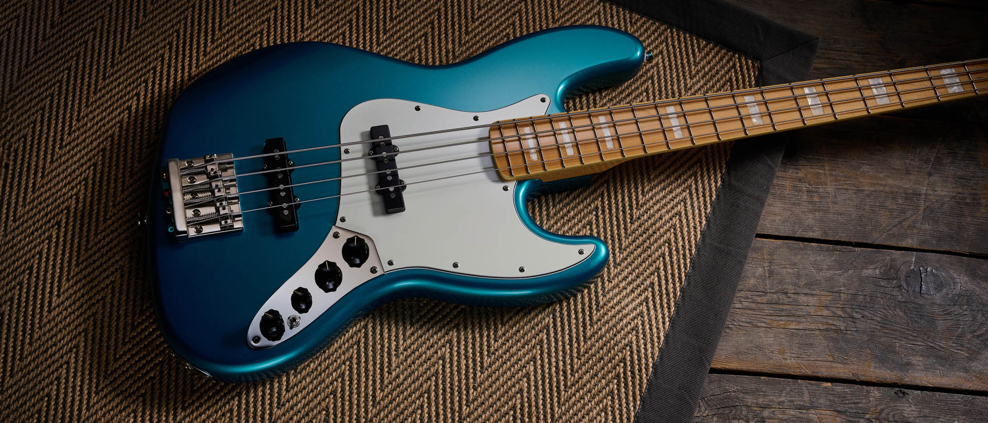 Squier Classic Vibe 70s Jazz Bass Active: finished in Ocean Turquoise, this keenly priced four-string is photographed in close-up with a patterned rug and wooden floor in the background.