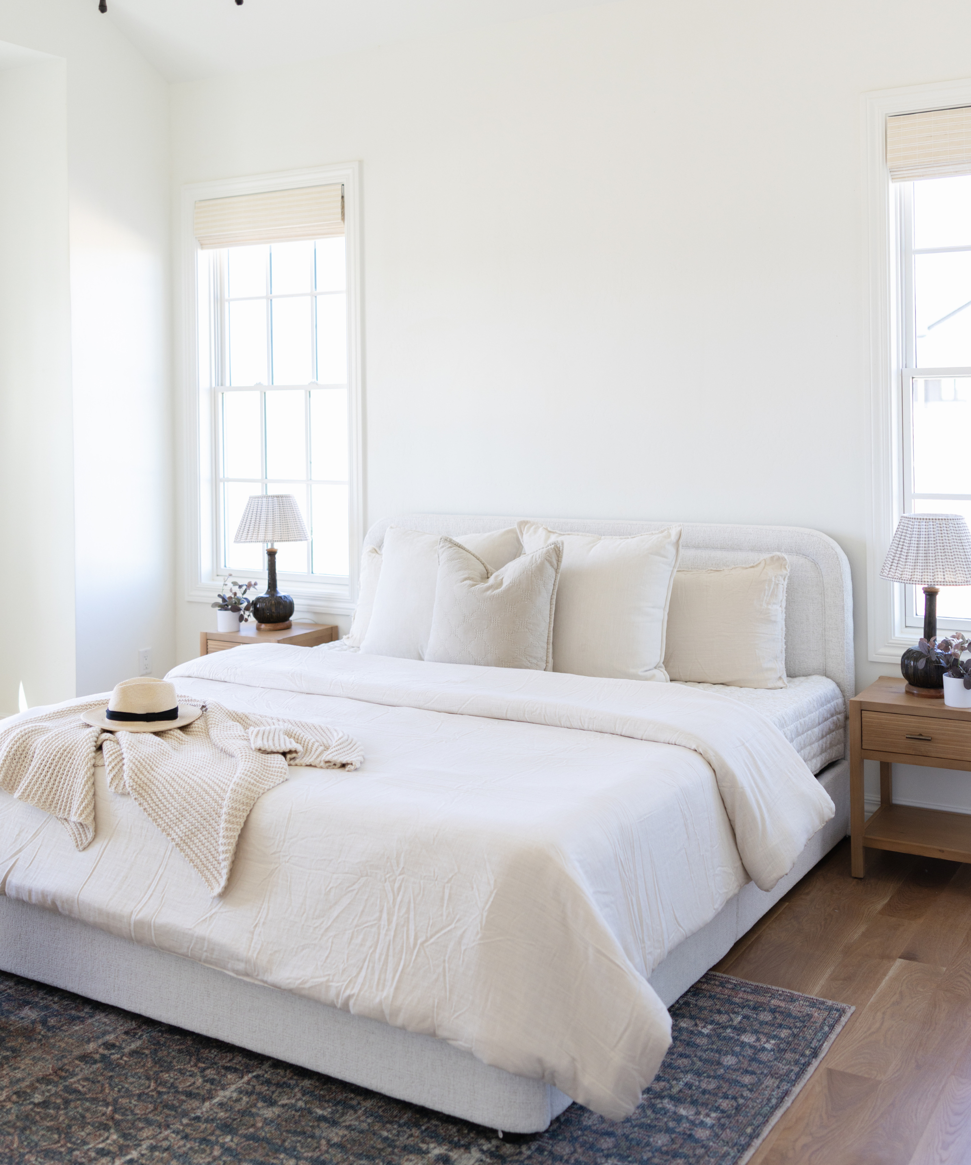 a neutral living room with white walls, white bedding, and symmetrical nightstands on either side of the bed