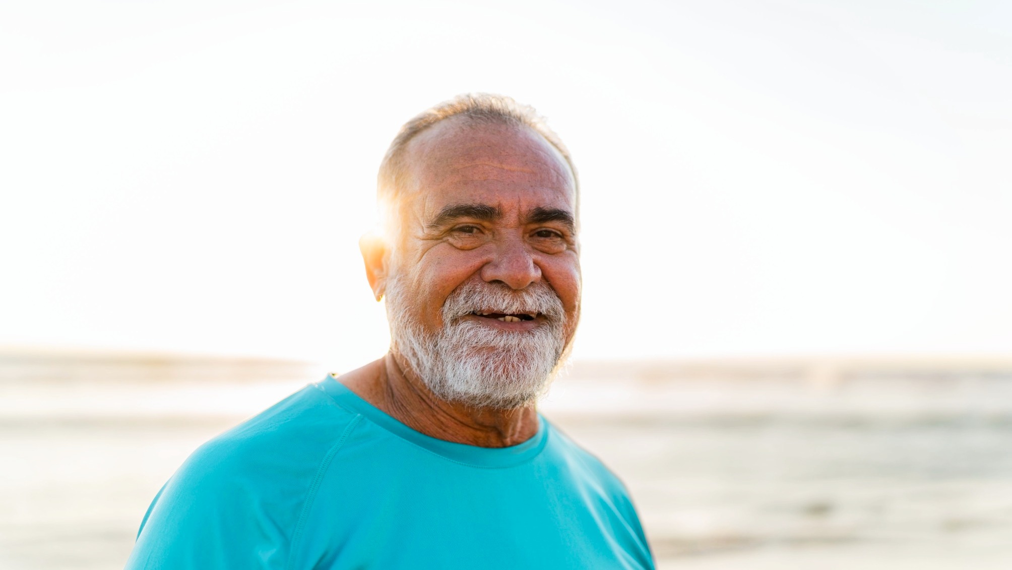 Portrait of a mature man in bright turquoise t-shirt on a beach