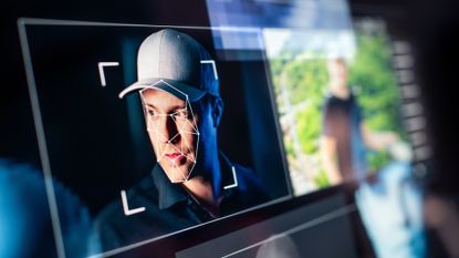 A visualization of an executive shown on a screen with their face mapped and tracked by software, to represent the creation of deepfakes.