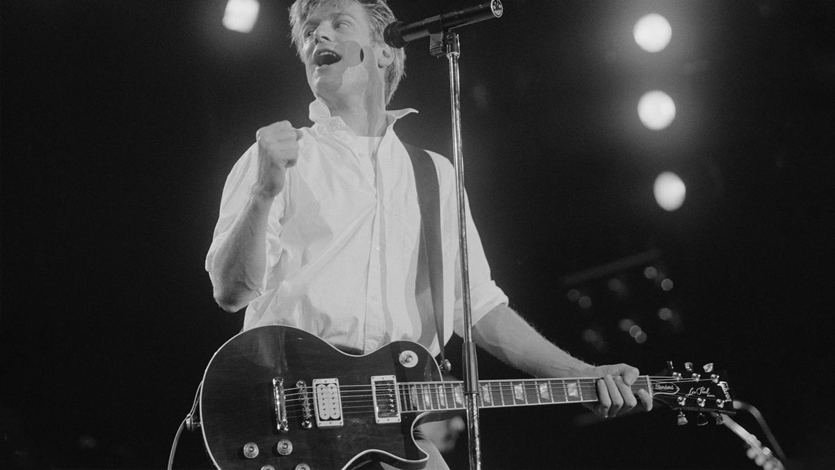 A black and white image of Bryan Adams onstage with a Les Paul, fist clenched