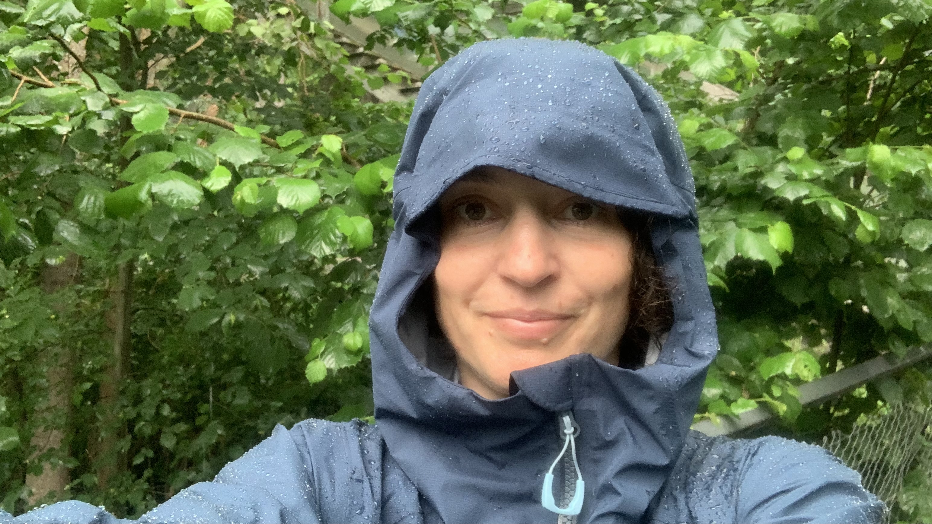 Hiker taking a selfies wearing the Rab Firewall Alpine jacket after a heavy rain