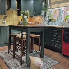 green kitchen with gold leaf splash back and kitchen table with bar stools
