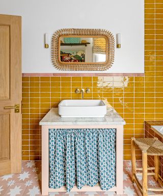 small bathroom with yellow metro tiles, pink floor tiles and rattan mirror frame