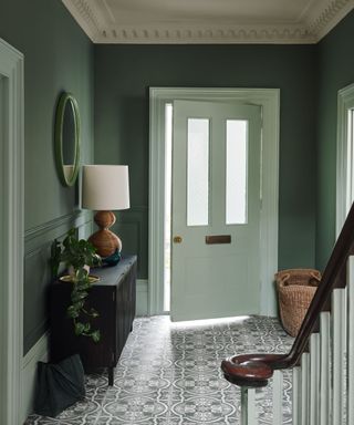 Green walls, white and black tiled floor, white front door, black table
