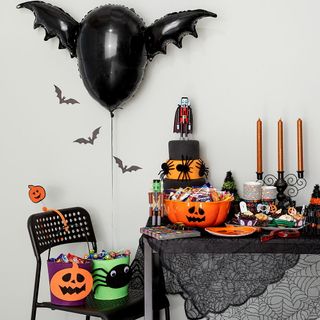 Halloween decorations and sweets setup on a table and black chair
