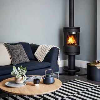 Living room with dark wood floor and blue denim sofa and woodburning stove