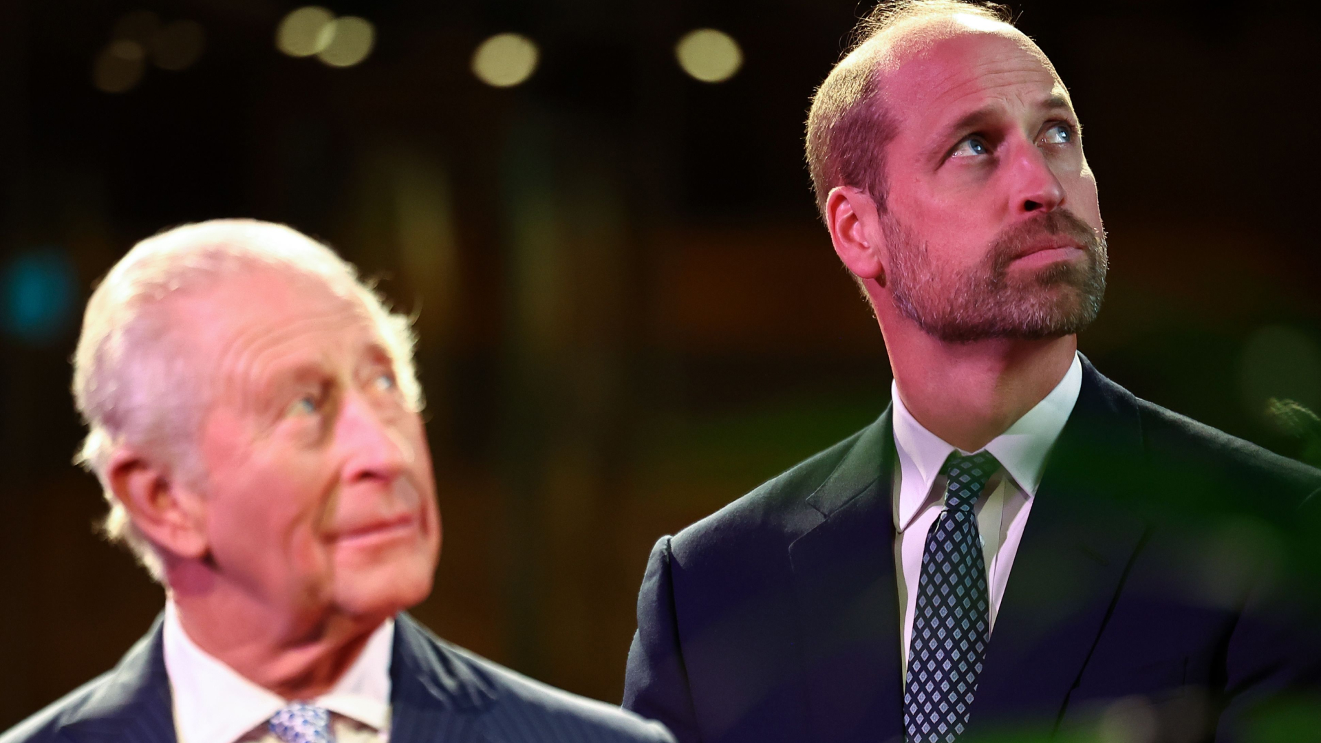 King Charles and Prince William both wear suits and spotted ties and look to the sky