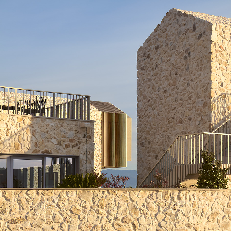 views of Pur residential recording studio, a family of structures in a cluster, made of stone and wood against blue Mediterranean skies