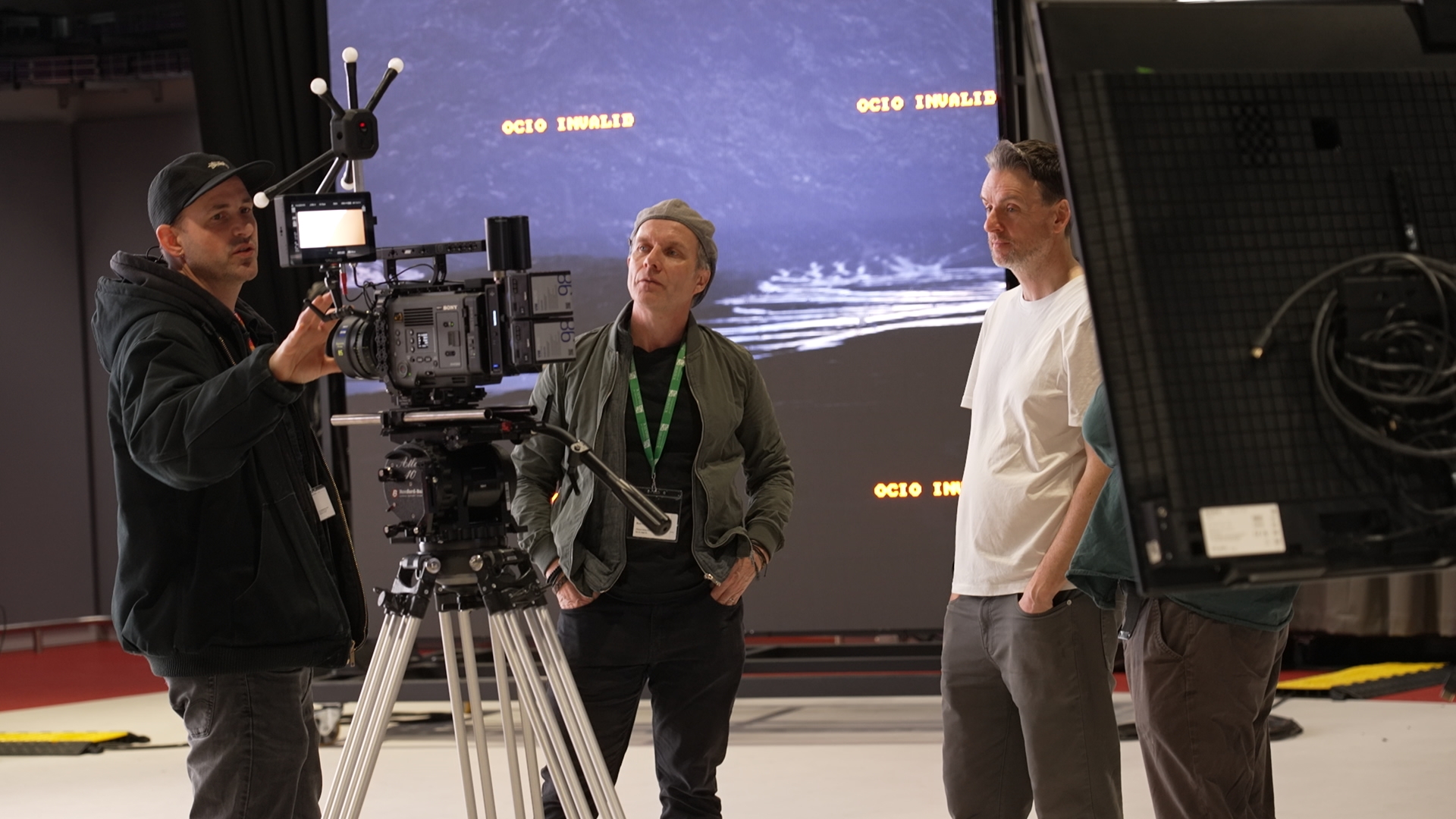 man with hat on directing a film with two other men