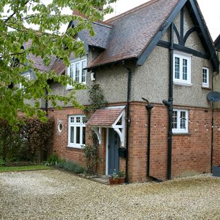 Front of semi-detached brick house with gravel driveway