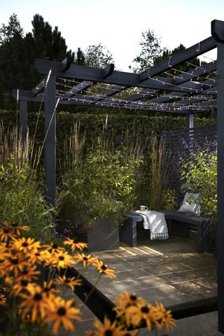 a pergola with fairy lights in a garden