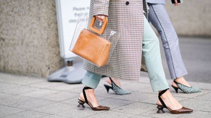 Two women walking down the street wearing heeled shoes.