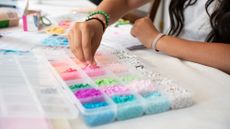 A teenager makes beaded bracelets