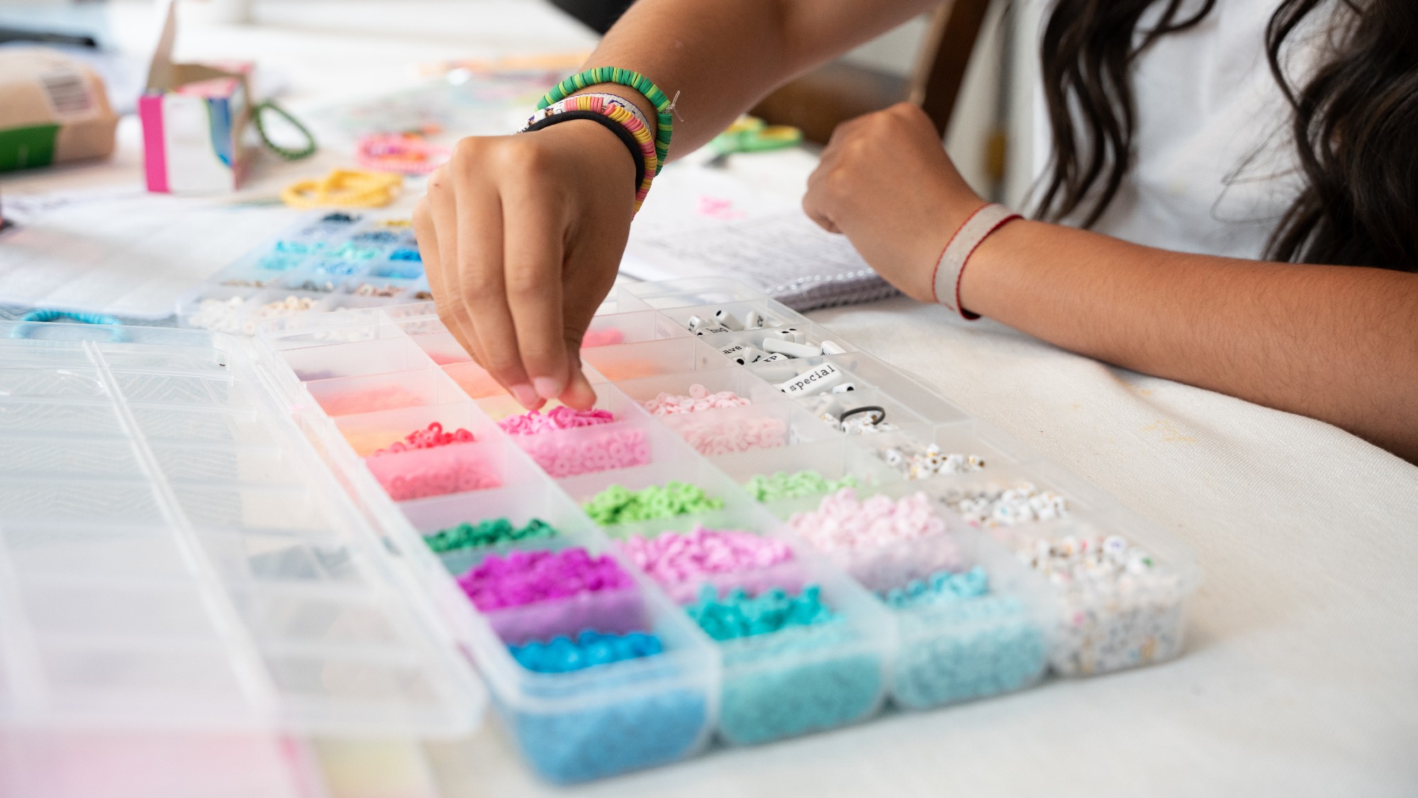 A teenager makes beaded bracelets