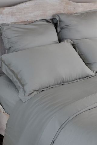 Dark grey silky bedding with wooden headboard close up