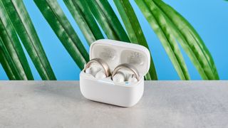 Soundcore AeroClip open-ear earbuds in champagne mist against a blue backdrop