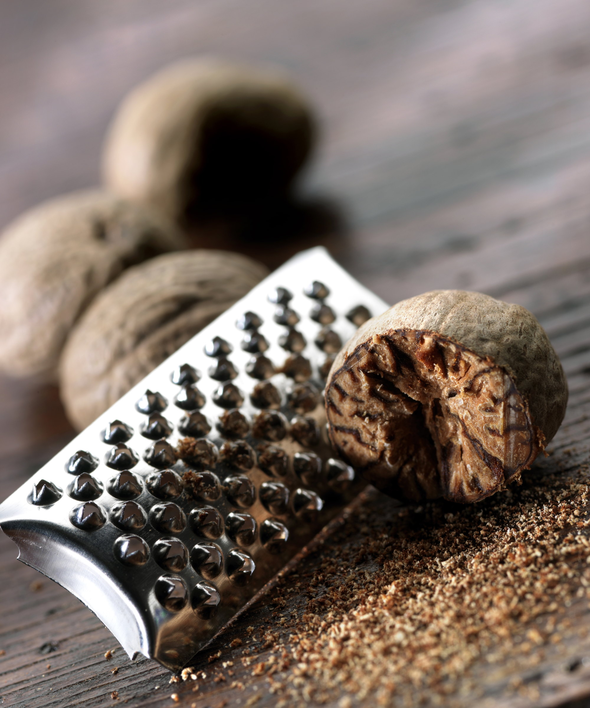 Grated nutmeg and grater on a wooden background