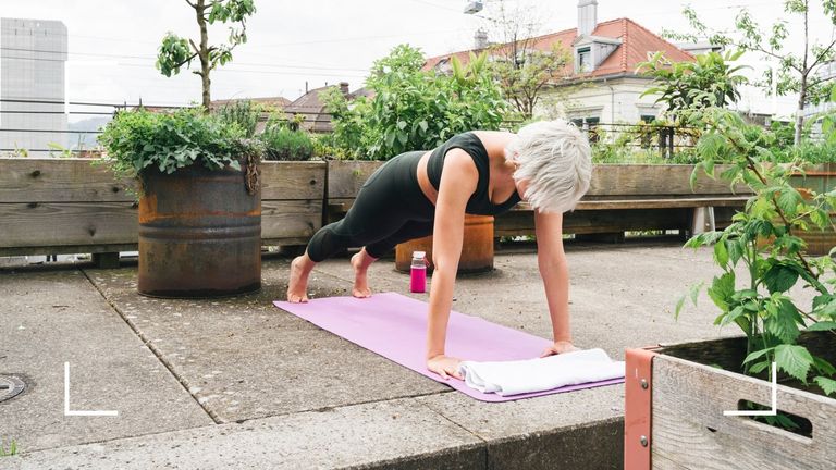 Woman doing Pilates for weight loss on roof terrace on pink yoga mat
