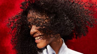 A woman smiles as she flicks her hair from side to side.