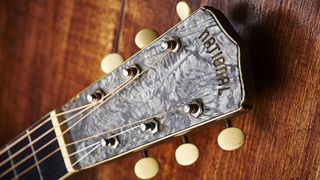 This model has a grey plastic pearl-effect headstock veneer with Art Deco-style National logo. The serial number is stamped on top of the headstock in this case