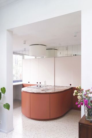 Minimal white kitchen with large red semi-circle island