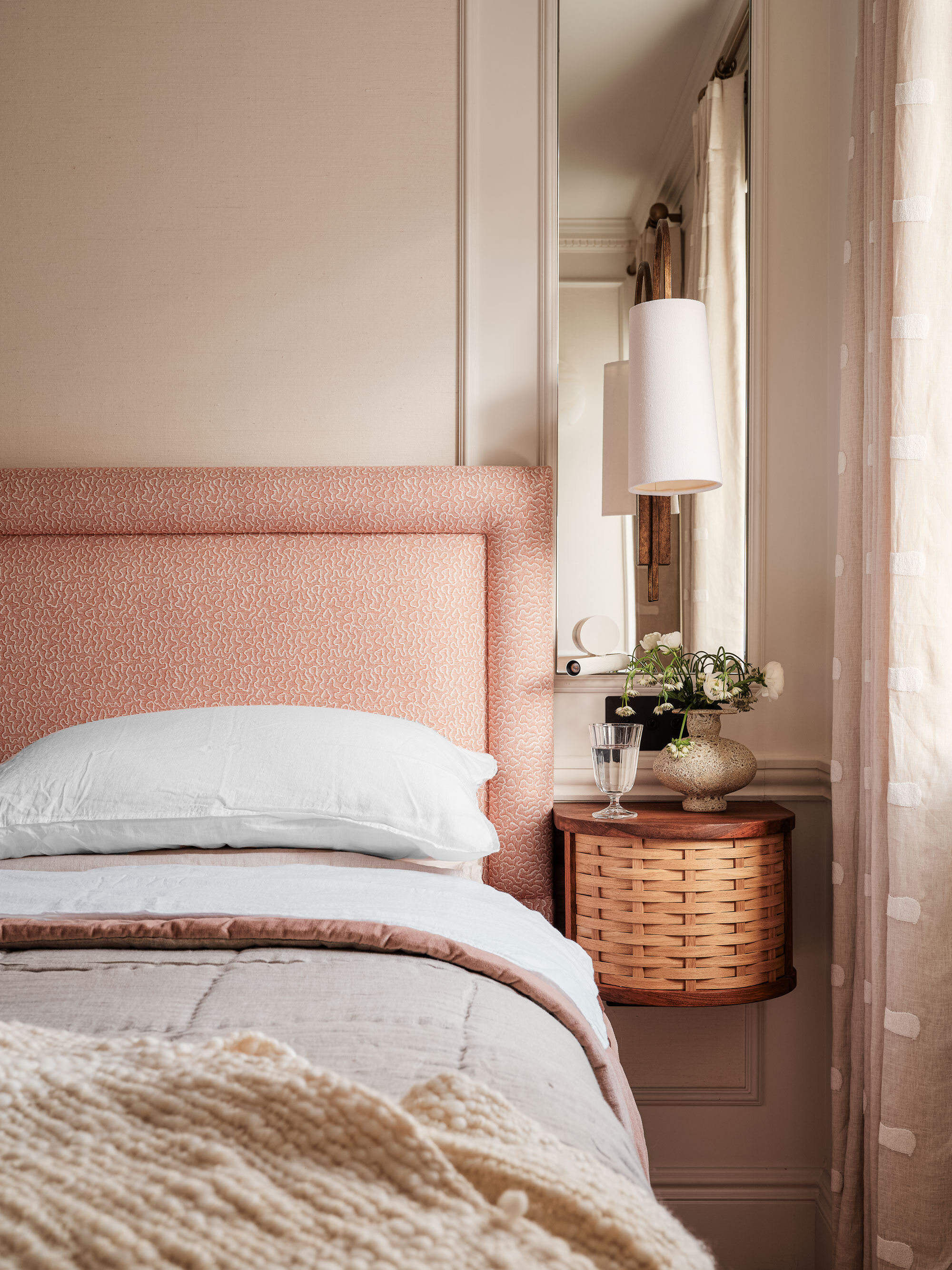 The main bedroom with subtle pink accents and woven side tables