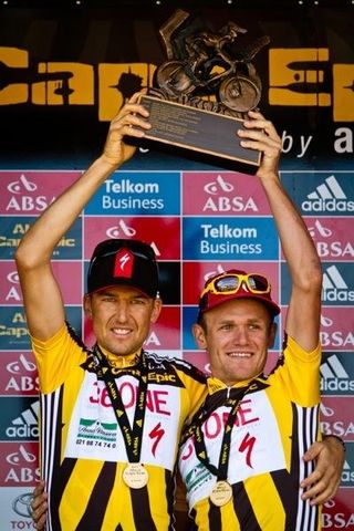 Christoph Sauser and Burry Stander hold up their Cape Epic trophy