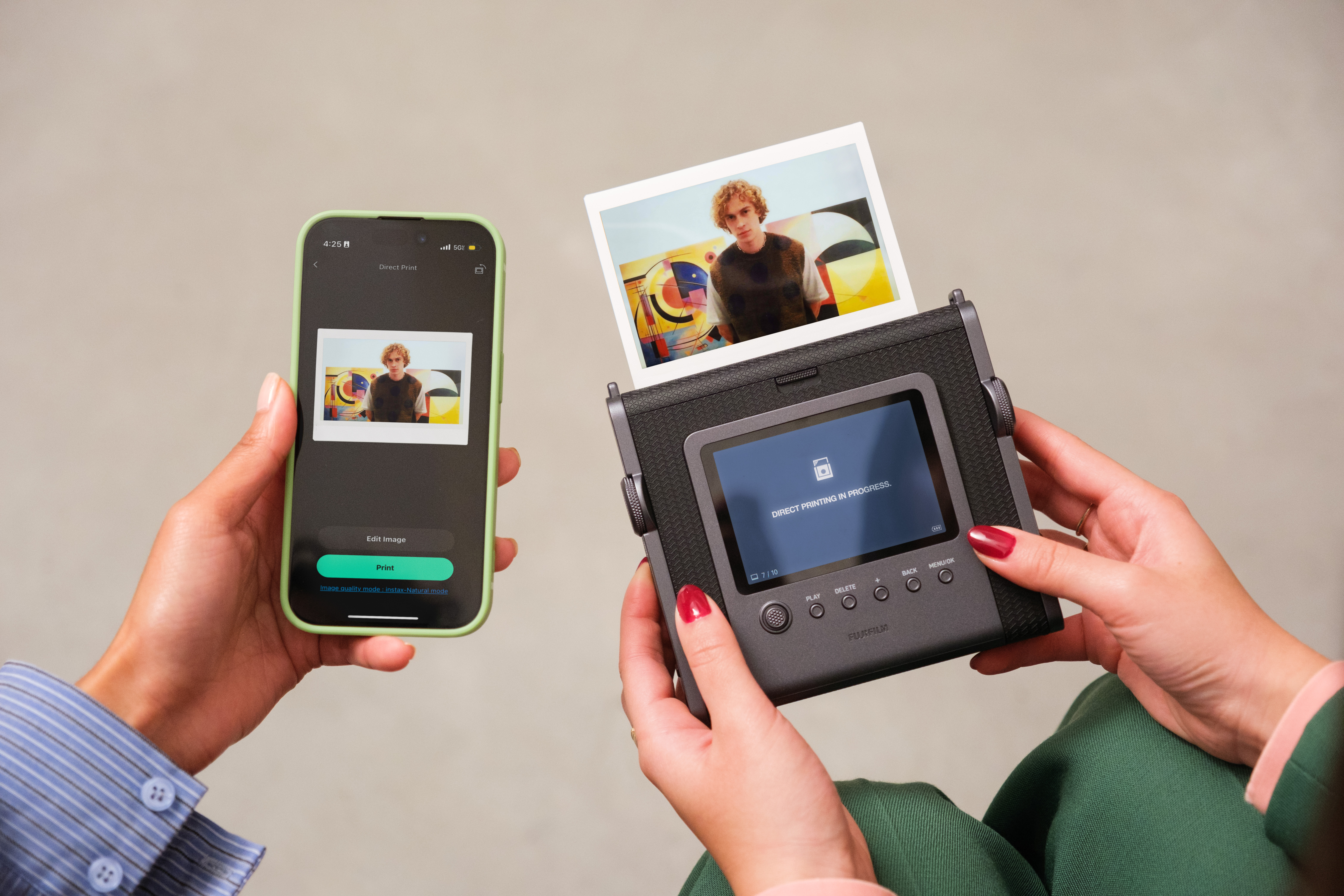 Fujifilm Instax Wide Evo instant camera's rear screen alongside a phone with the app, printing a photo