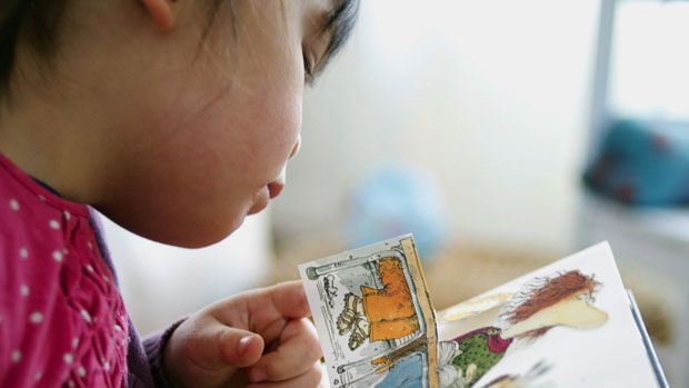 A young girl reads a children&amp;#039;s book